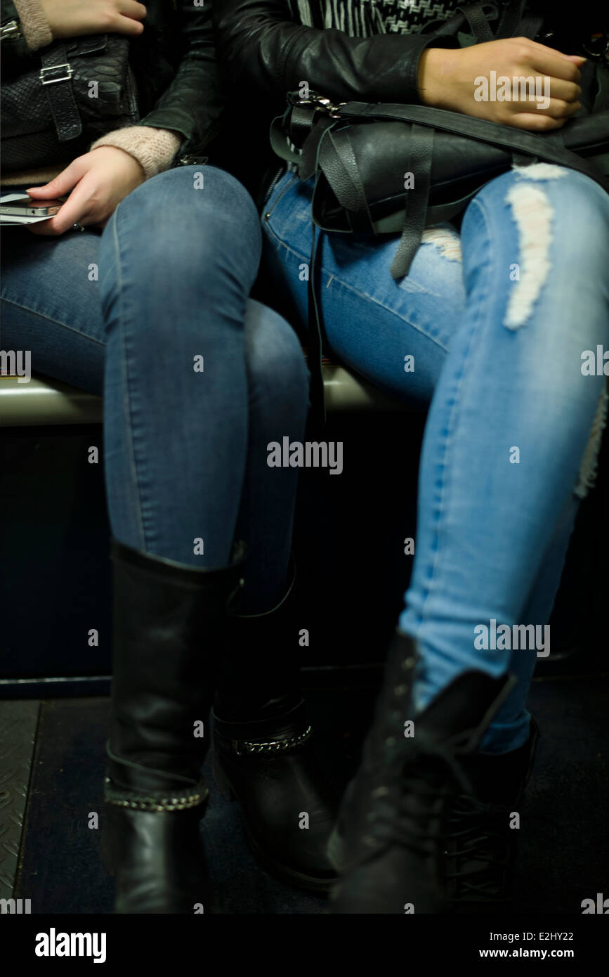 Women wearing jeans and boots sitting side by side Stock Photo - Alamy