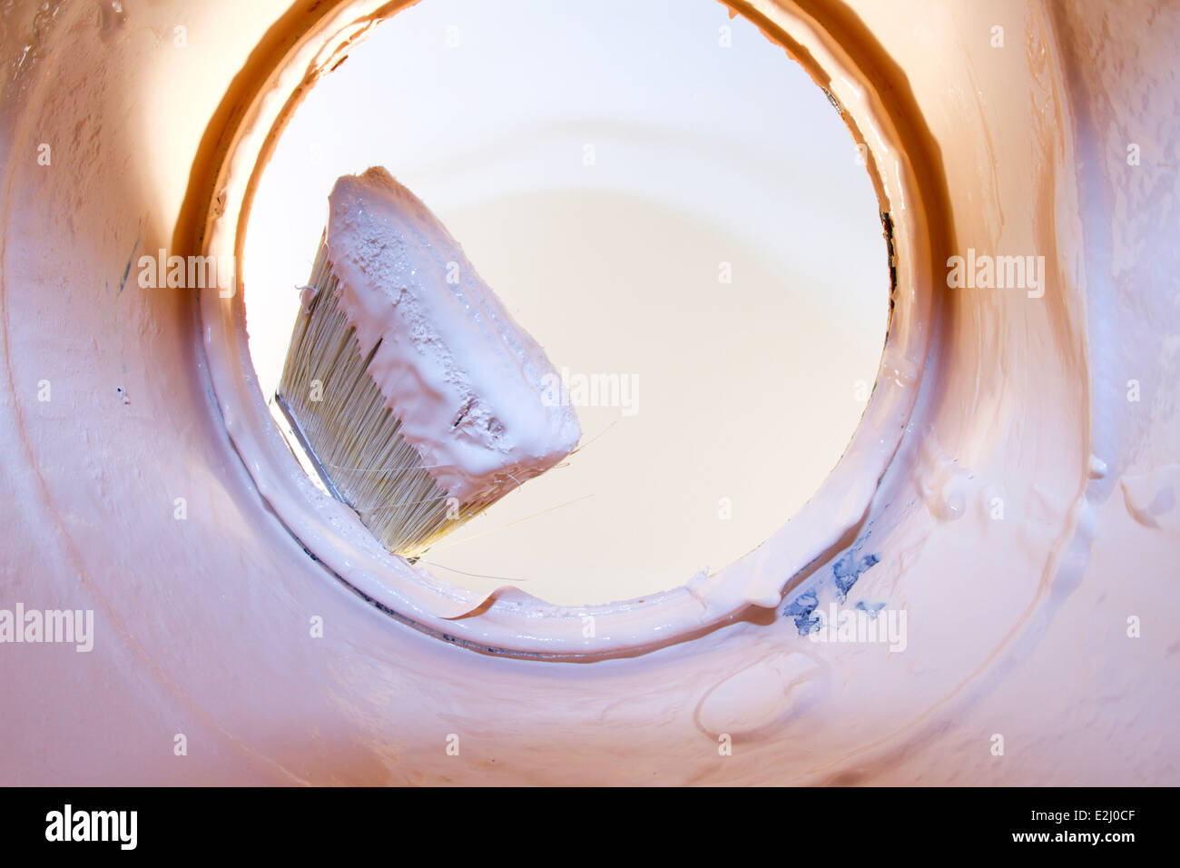 View from inside a paint can of a paint brush tipped with pink paint