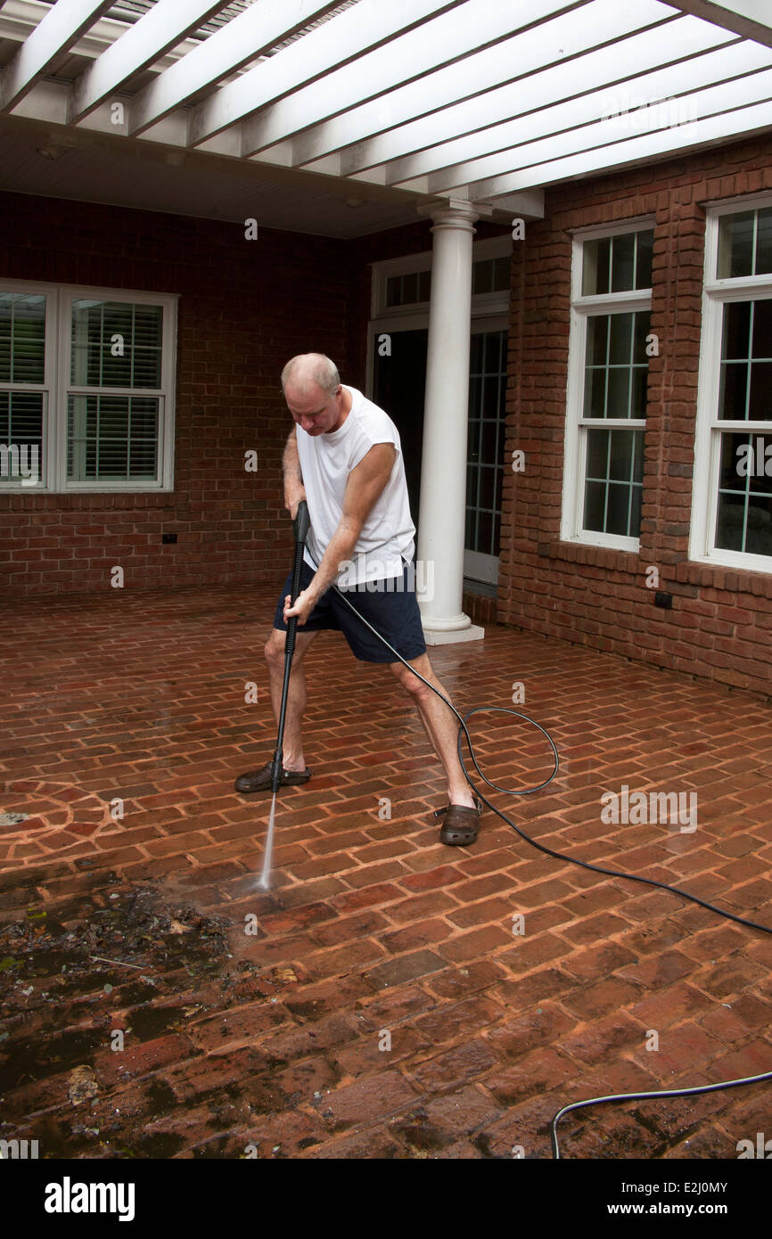 Man In Shorts Power Washing Dirt From Brick Patio Stock Photo