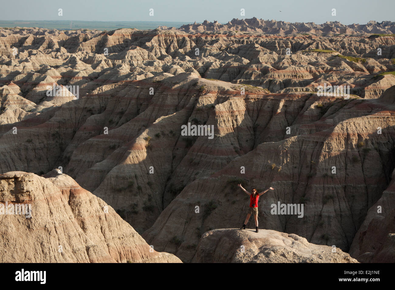 Woman in red shirt looking across Badlands National Park in South Dakota Stock Photo