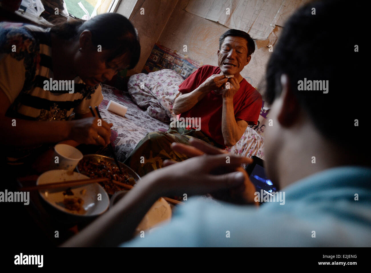 Residents have supper in the villa areas of Wulitai new village in Yinchuan, northwest China's Ningxia Hui Autonomous Region, June 10, 2014.     There are over 30 villas in Wulitai new village with one third uncompleted due to the default of construction payments. Those villas are now rent out to migrant workers. A 200-square-meter villa was seperated into several rooms, and the rent of each one is about 300 yuan (about 48.18 U.S.dollars). For migrant workers who have no access to cheap bungalows or can't afford apartments, such room is a good re Stock Photo