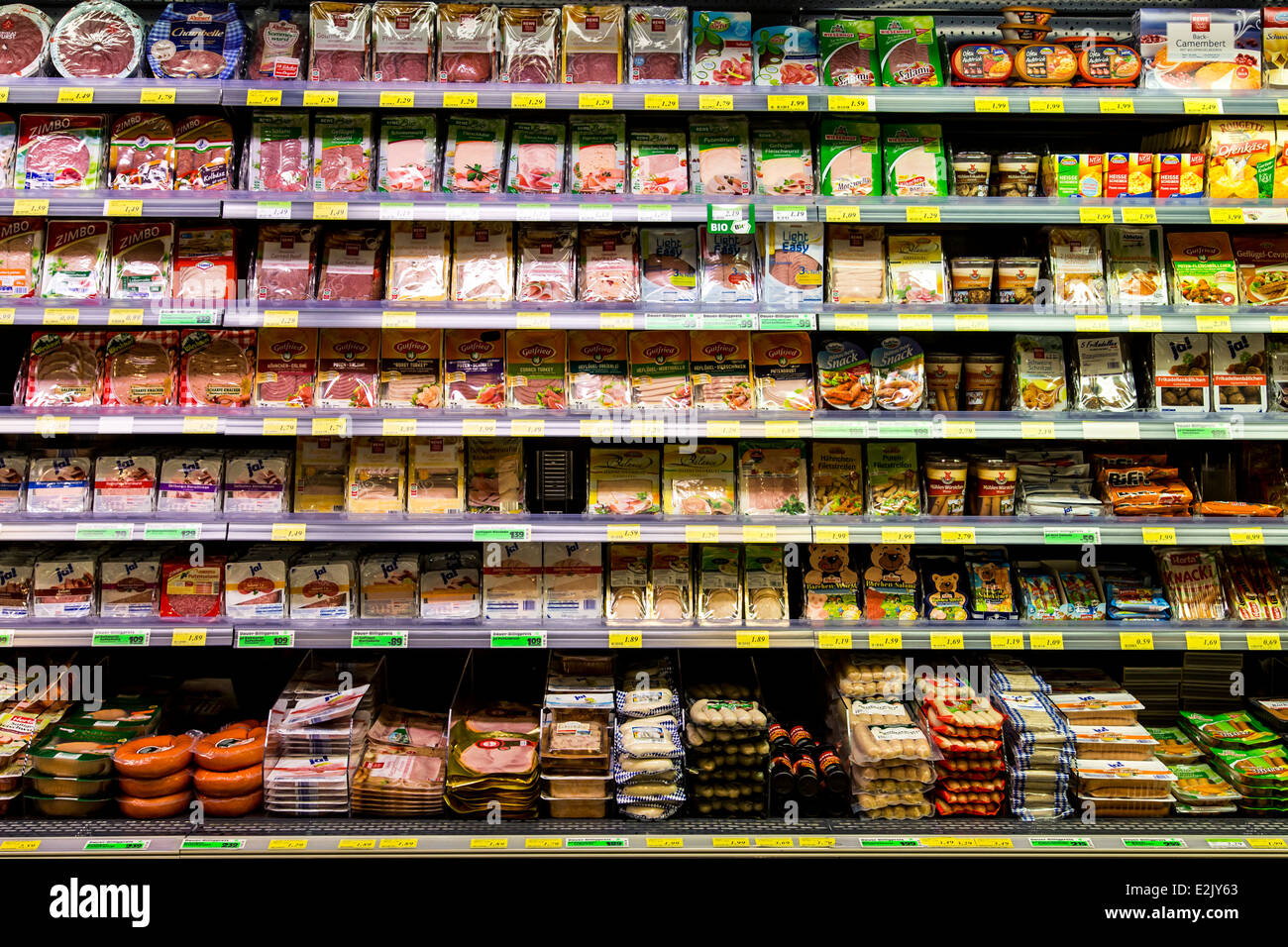 Shelf with food in a supermarket. Packed meat, sausages, ham Stock