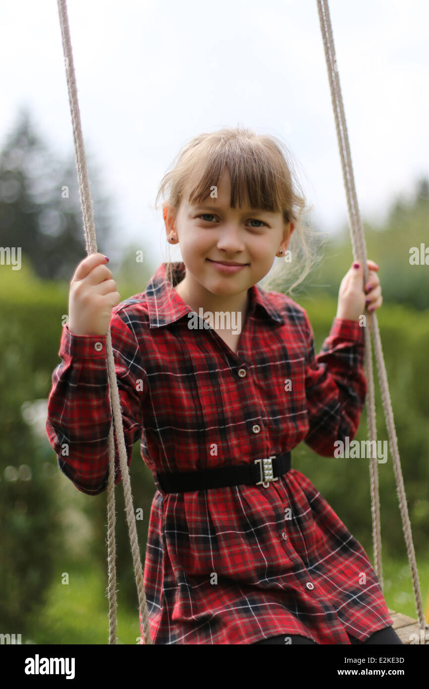 Little girl swinging on a swing on summer day Stock Photo