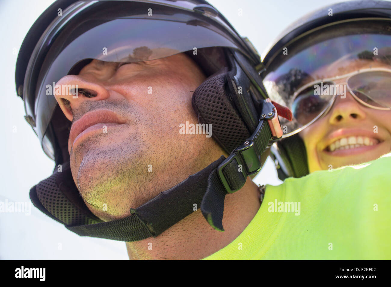 young woman man [driving bike] [wearing helmet helmets sunglasses] faces portraits 'riding bike' sunlight day safe safety  smile Stock Photo