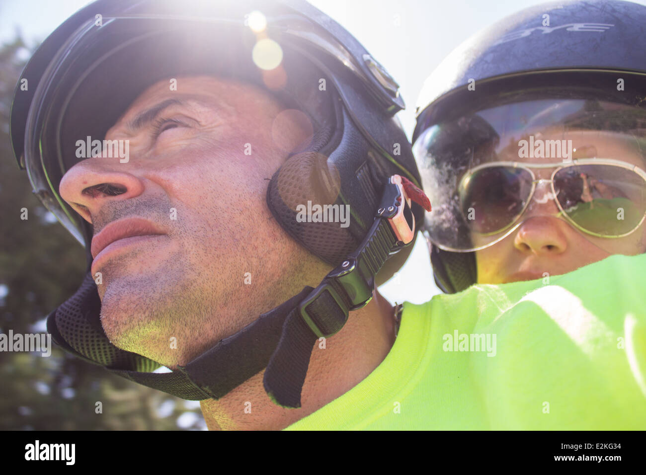 young woman man [driving bike] [wearing helmets] faces portraits 'riding bike' sunlight day safe safety Stock Photo