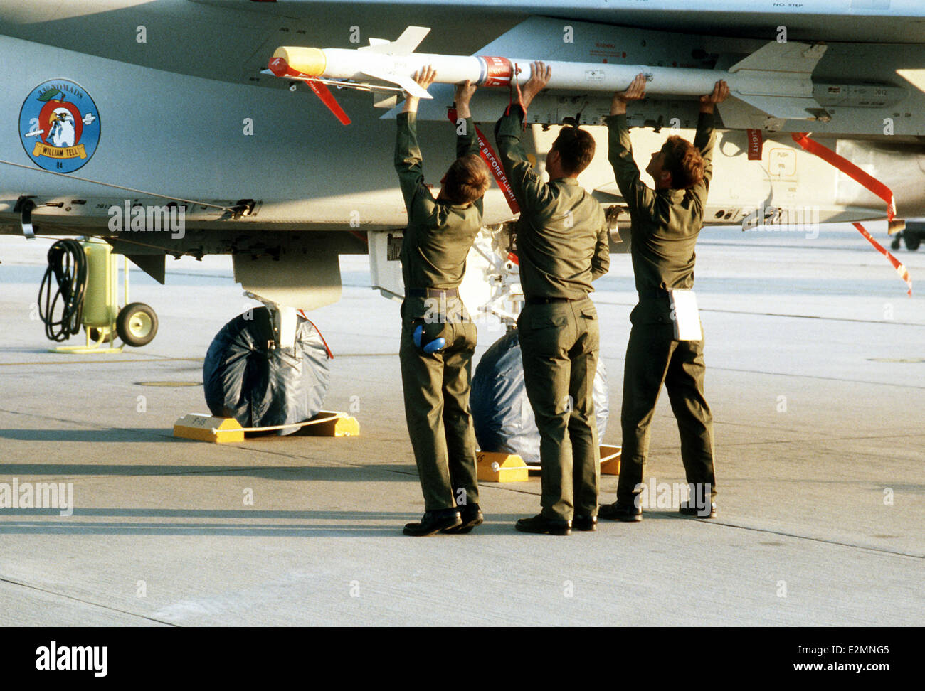Tactical Fighter Wing weapons crew loads an AIM-9 Sidewinder missile onto the wing pylon of an F-15 Eagle aircraft Stock Photo