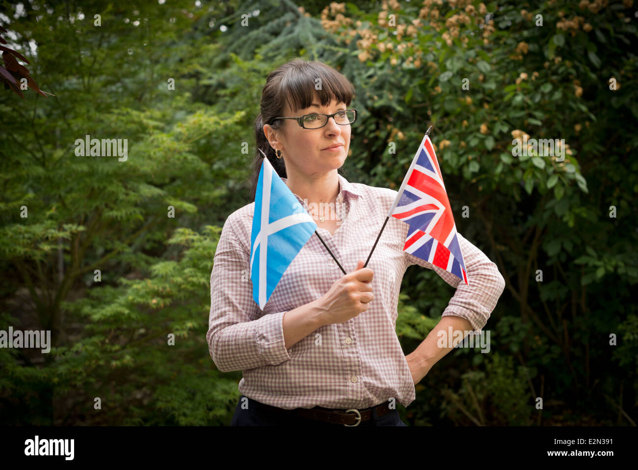 Young woman looking at a Scottish and British flag deciding how to vote in the Scottish independence referendum Stock Photo