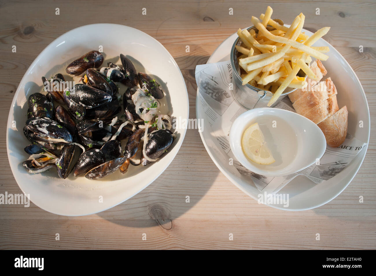 Mussels or Moules cooked in in white wine with parsley and accompanied with chips or French fries and white bread. Stock Photo