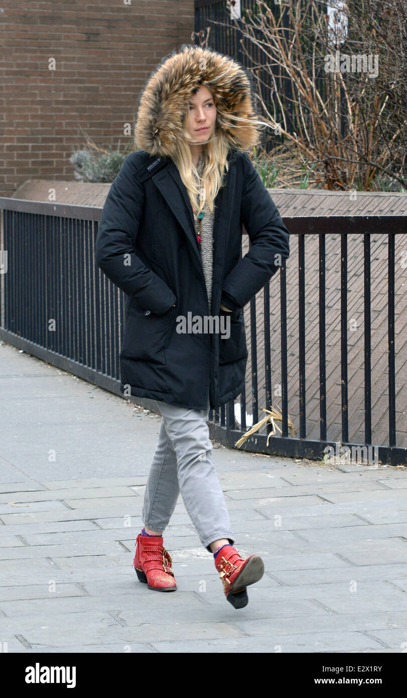 Sienna Miller wrapped up warm in a fur lined parker jacket and walking in  embroidered red and gold ankle boots, stops at a cash Stock Photo - Alamy