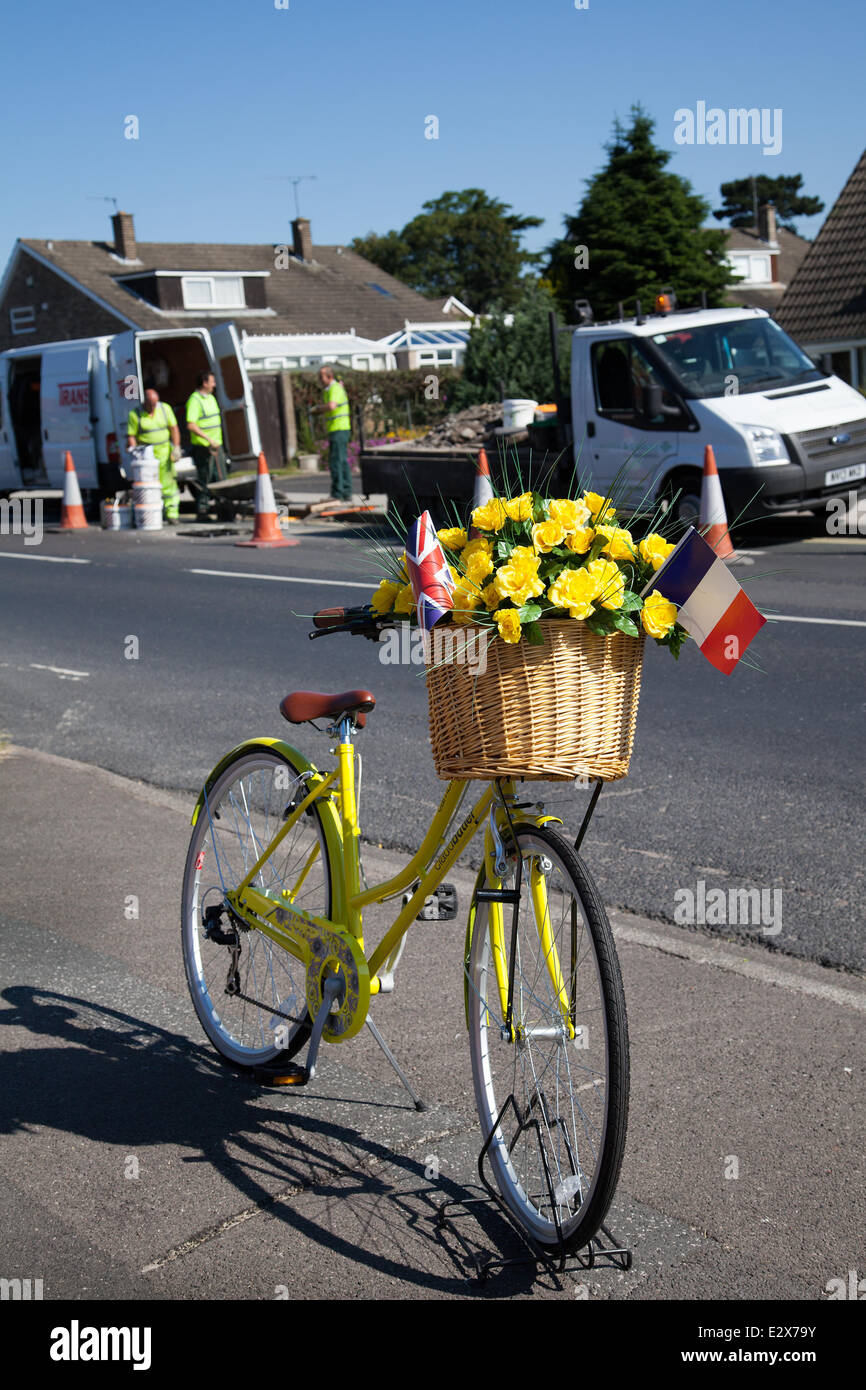Women's floral decorated yellow bicycle in York, Yorkshire, UK. 21st June, 2014.  Maintenance crew carrying out Saturday Road repairs on the  Tour de France route.  A total of £4million has been allocated by eight Yorkshire councils to get the region’s roads repaired and the route ready for Tour de France in July.  The money is being spent to ensure that the 389 kilometres of tarmac to be used for the 2014 Tour’s Grand Depart, will be pothole free. The route is now being lined with yellow flowers, wickerwork baskets and bikes. Stock Photo