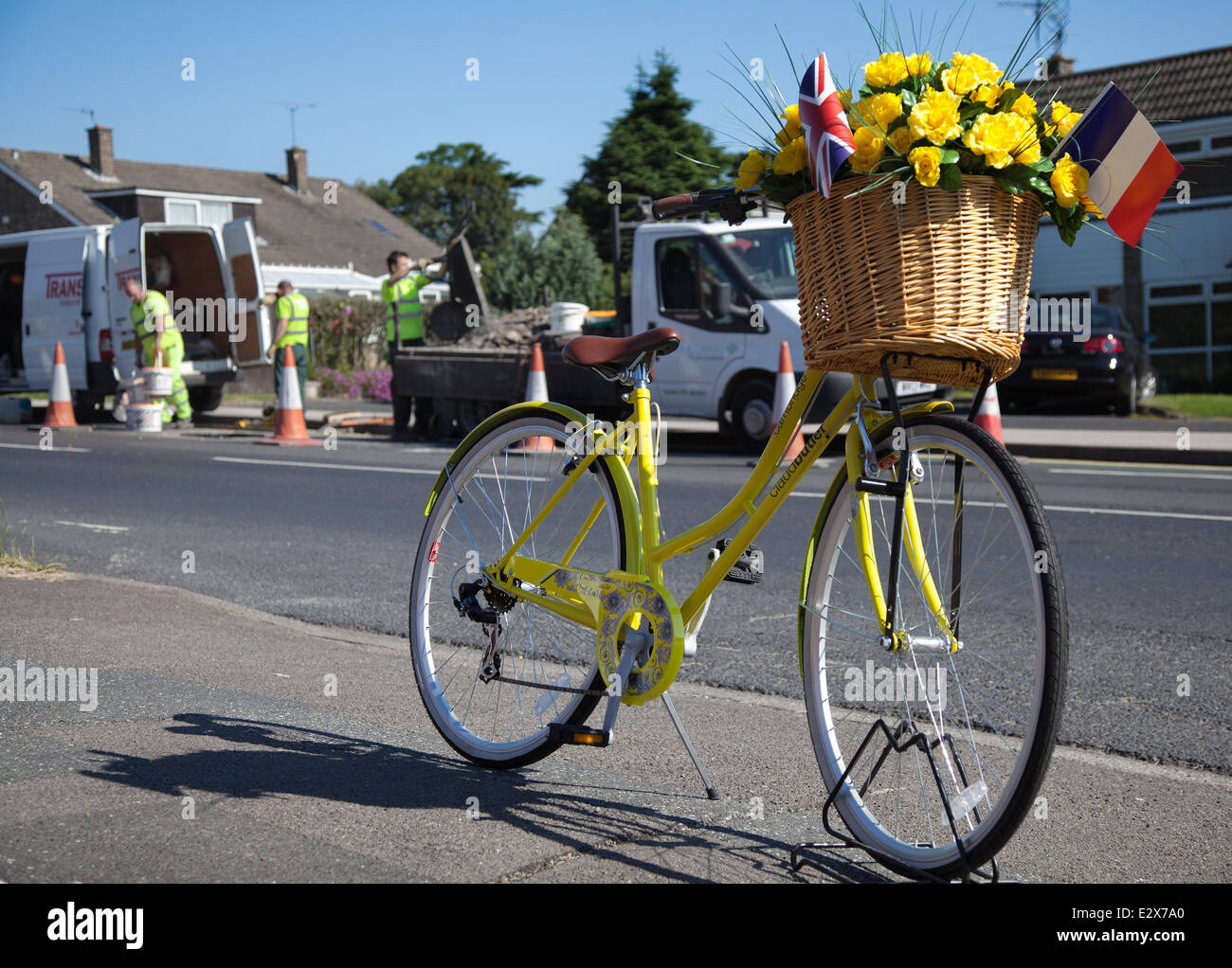 Women's floral decorated yellow bicycle in York, Yorkshire, UK. 21st June, 2014.  Maintenance crew carrying out Saturday Road repairs on the  Tour de France route.  A total of £4million has been allocated by eight Yorkshire councils to get the region’s roads repaired and the route ready for Tour de France in July.  The money is being spent to ensure that the 389 kilometres of tarmac to be used for the 2014 Tour’s Grand Depart, will be pothole free. The route is now being lined with yellow flowers, wickerwork baskets, bunting and bikes. Stock Photo