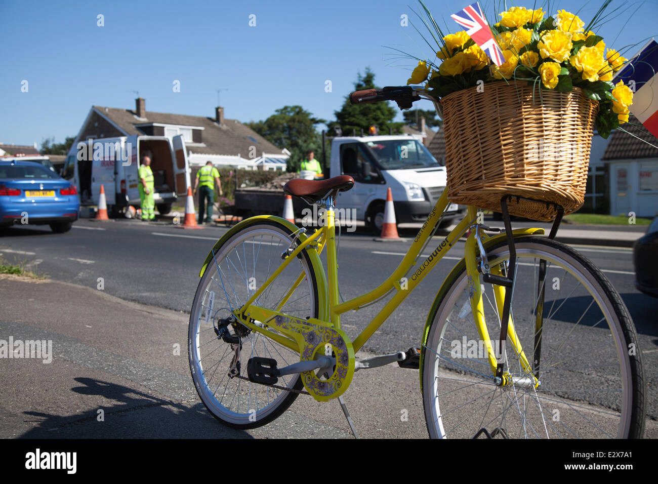 Women's floral decorated yellow bicycle in York, Yorkshire, UK. 21st June, 2014.  Maintenance crew carrying out Saturday Road repairs on the  Tour de France route.  A total of £4million has been allocated by eight Yorkshire councils to get the region’s roads repaired and the route ready for Tour de France in July.  The money is being spent to ensure that the 389 kilometres of tarmac to be used for the 2014 Tour’s Grand Depart, will be pothole free. The route is now being lined with yellow flowers, baskets, bunting and bikes. Stock Photo