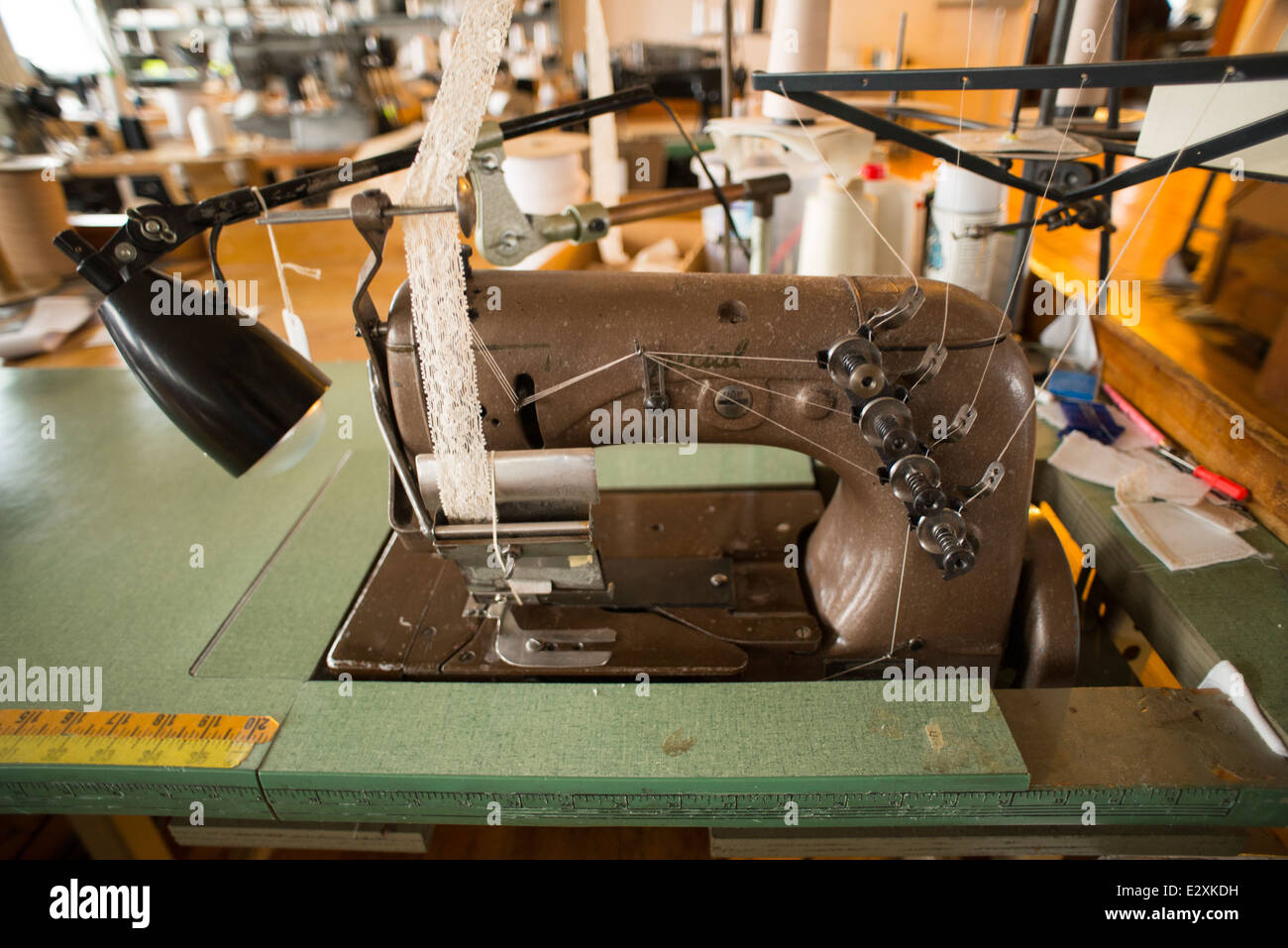 An antique, brown Singer sewing machine attached to an antique table sits in a corset factory in Cortland, NY. Stock Photo