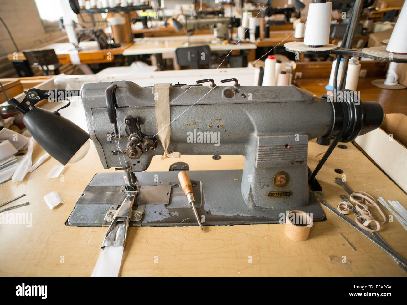 An antique, gray Singer sewing machine attached to an antique table sits in a corset factory in Cortland, NY. Stock Photo