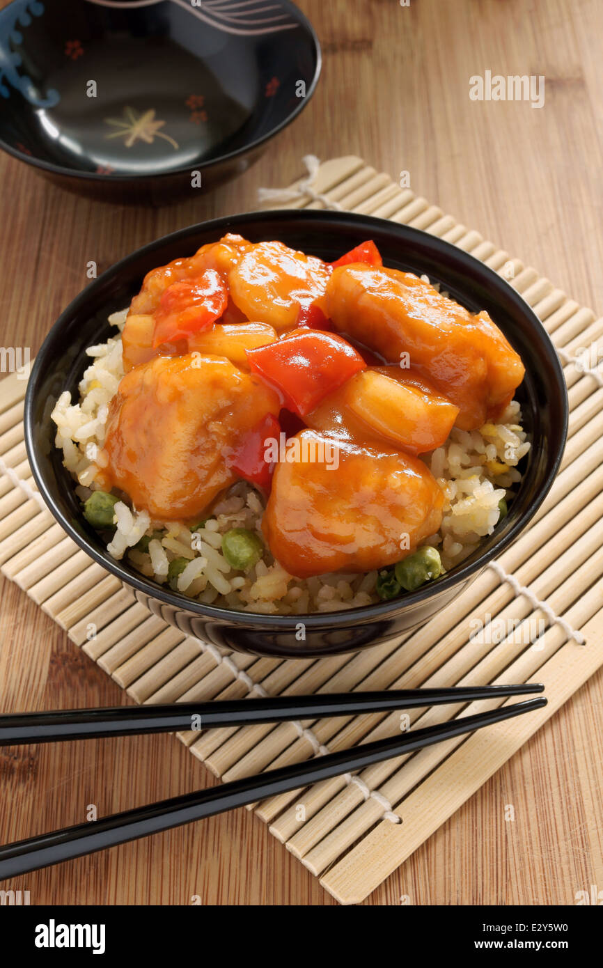 Sweet and sour chicken Cantonese style with egg fried rice in a lacquer bowl with chopsticks Stock Photo