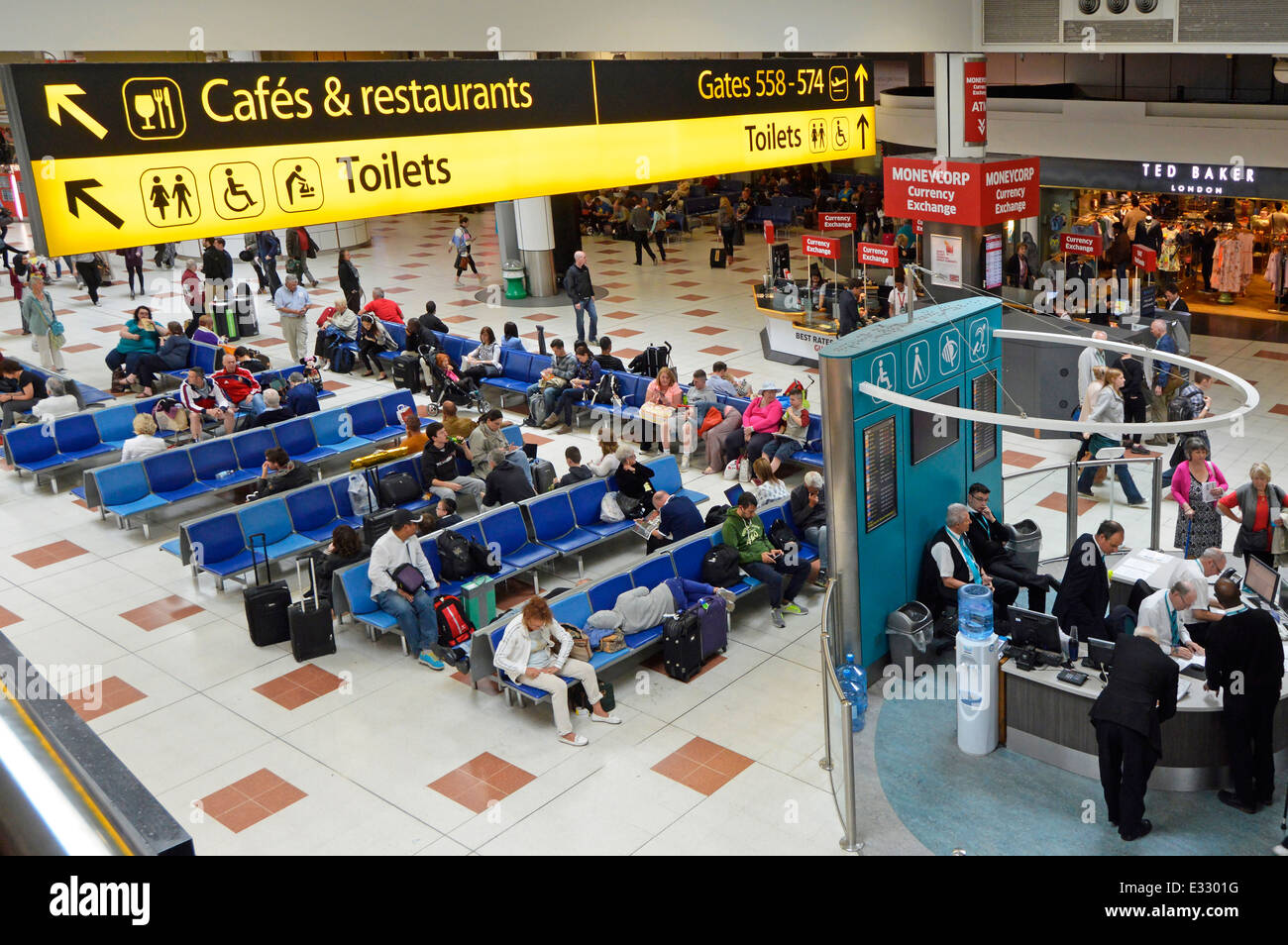 Seating area below cafes restaurants and toilet signs at Gatwick Airport North Terminal departure lounge and shopping concourse Stock Photo