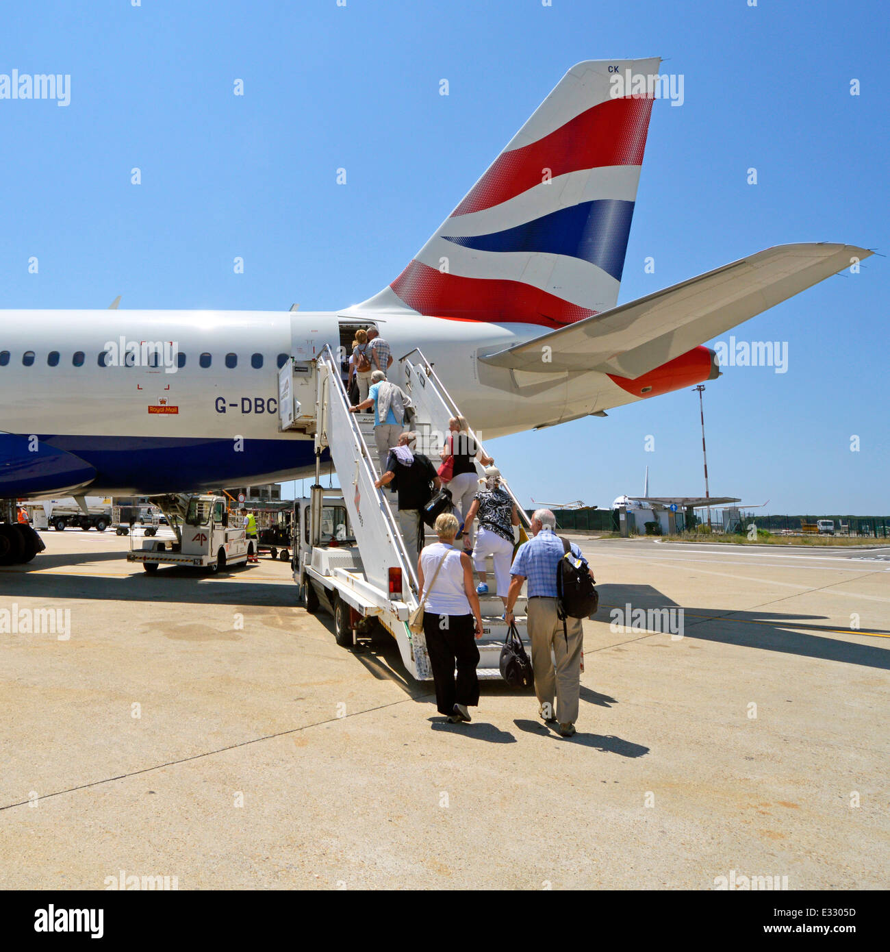 Passengers boarding British Airways aircraft via rear access door having been bussed out from terminal to use mobile staircase Rome Airport Italy Stock Photo