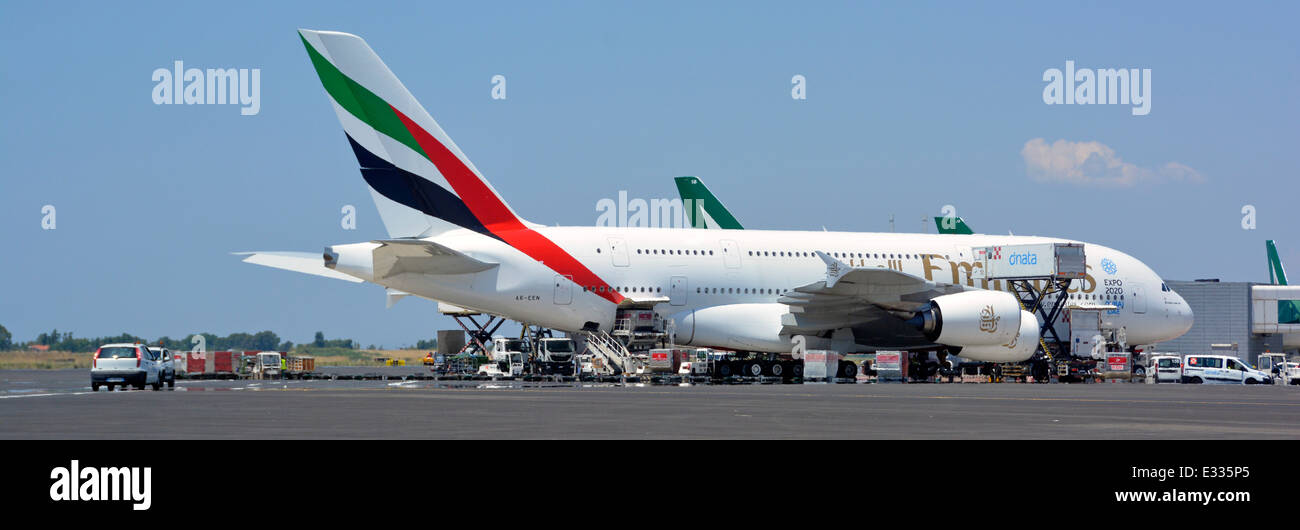 Emirates airline logo Airbus A380 double decker wide body four engine jet airplane airport apron stand ground crew attend Rome Fiumicino Airport Italy Stock Photo