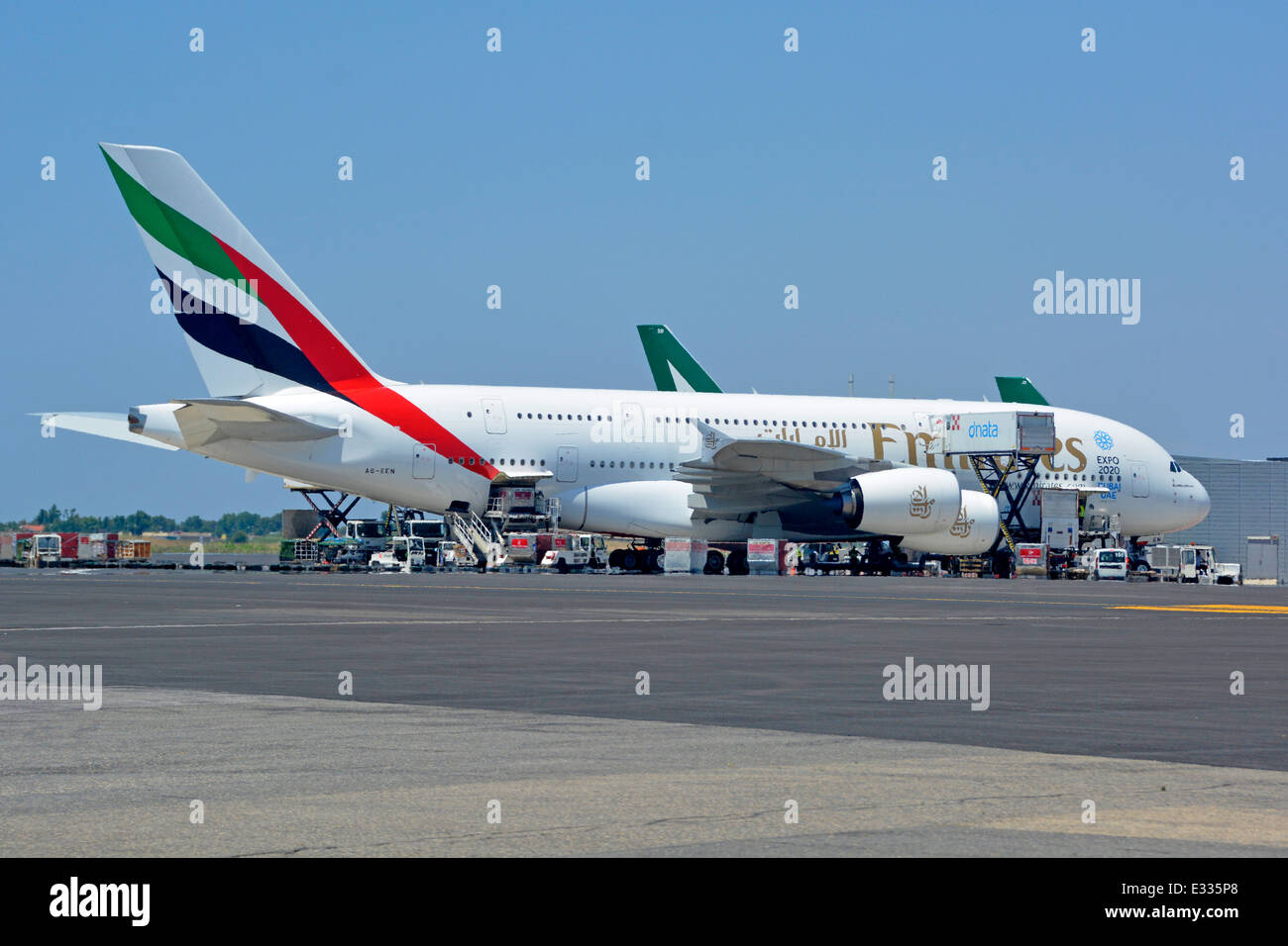 Emirates logo on Airbus A380 double deck wide body four engine jet airplane airport apron stand ground crew in attendance Rome Fiumicino Airport Italy Stock Photo