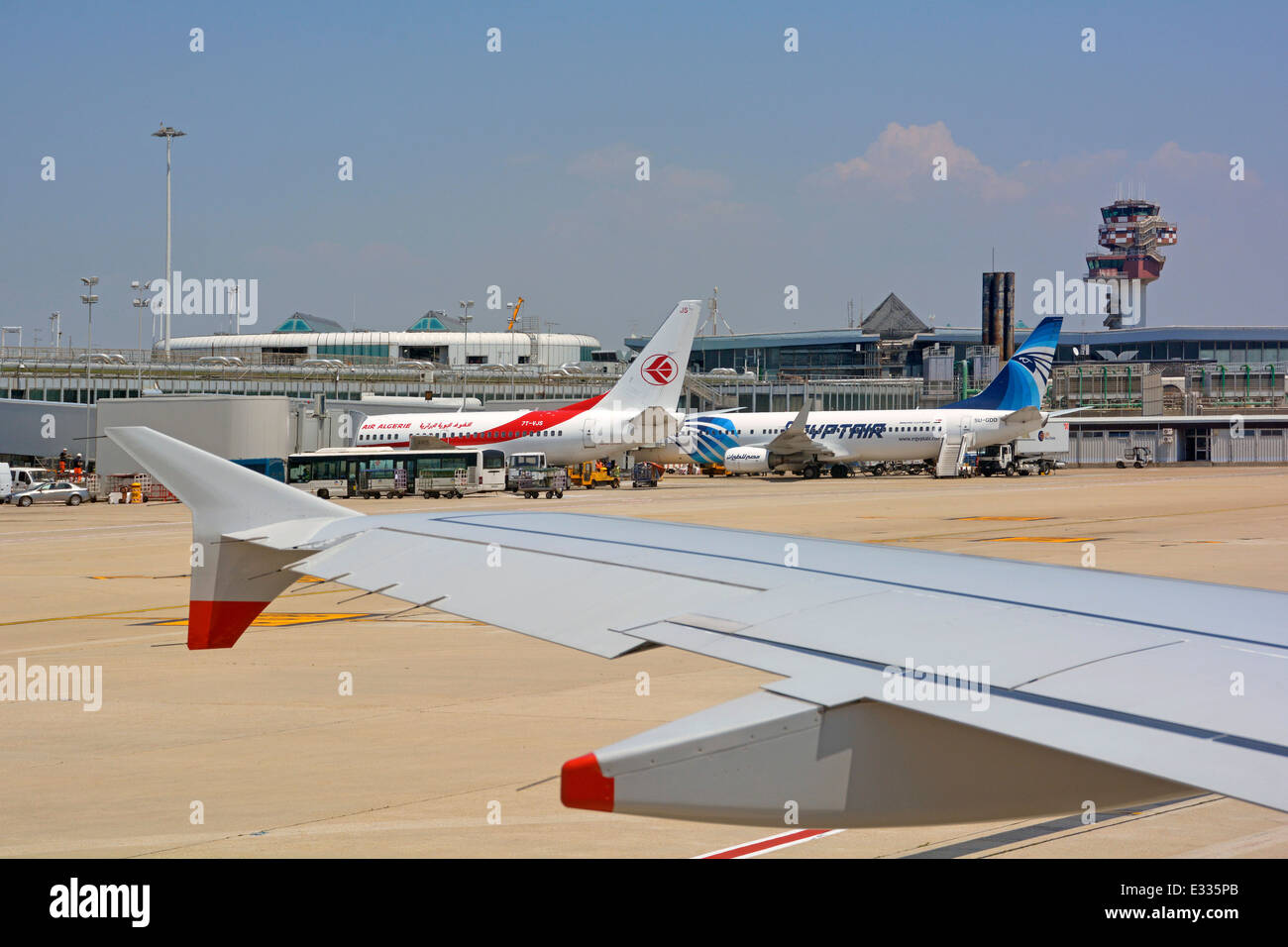 View from passenger jet airplane taxiing to Italian runway passing control tower & aircraft at terminal building Rome Fiumicino Airport Italy Stock Photo