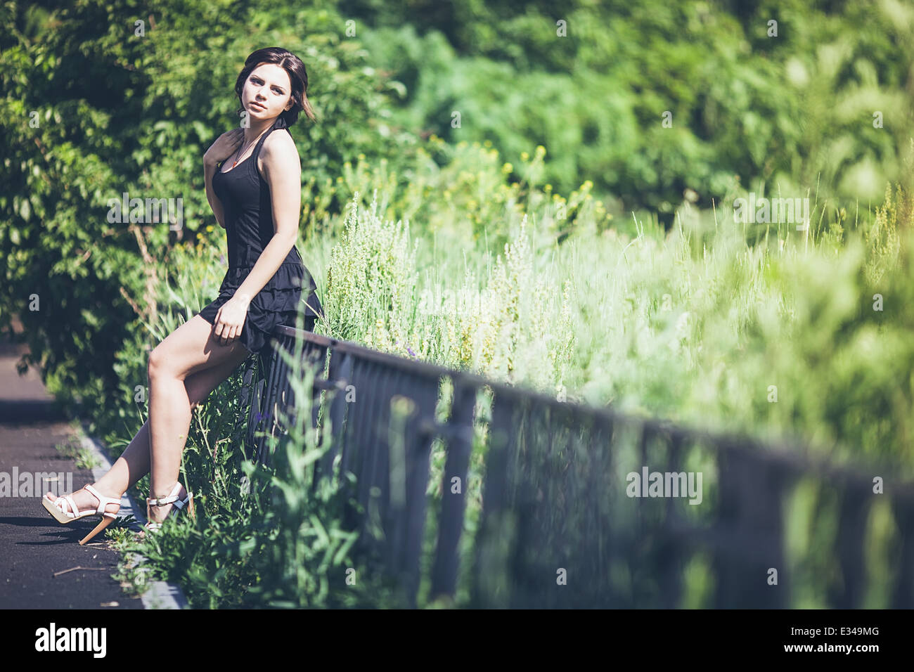 Girl in black dress on fence Stock Photo