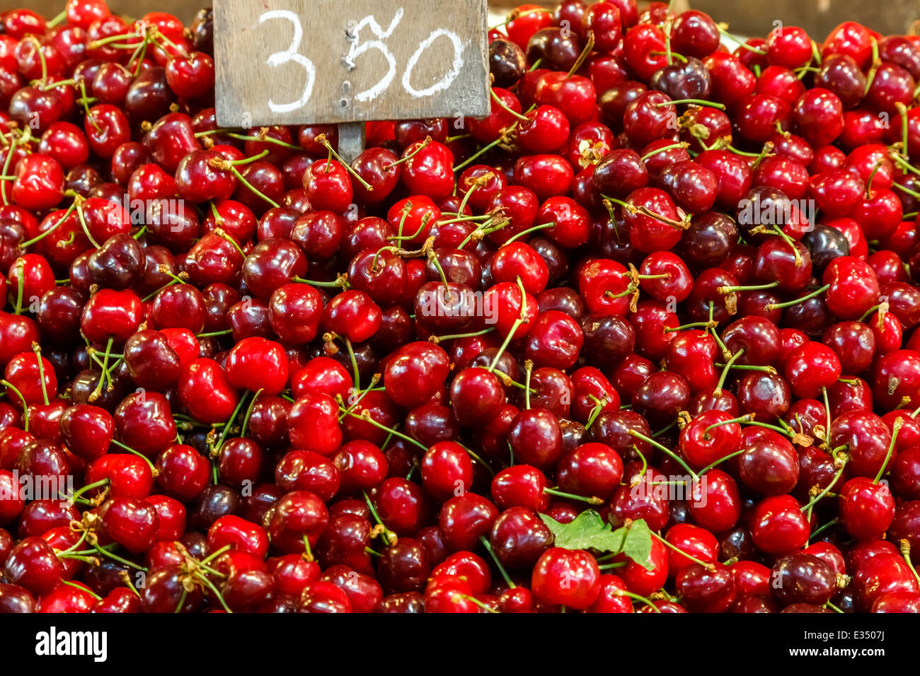 Red cherries in food market with price tag as a background texture Stock Photo