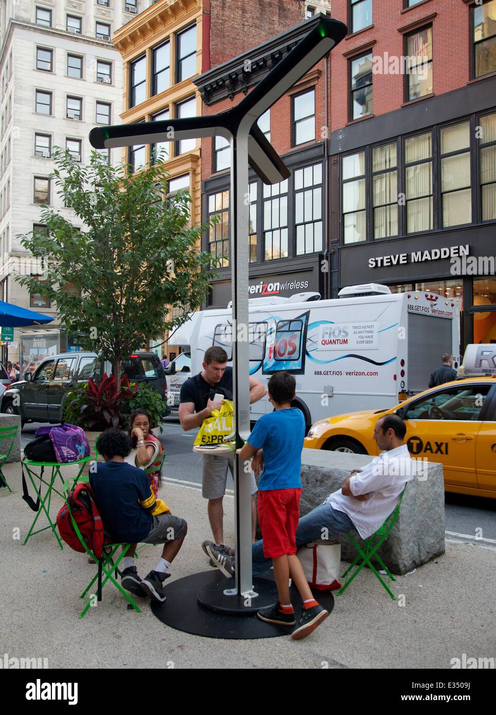 AT&T introduce solar-powered charging stations to New Yorkers. As keeping the mobile life going becomes ever more important  both to wireless customers and the providers who serve them AT&T says it has a new way to keep New Yorkers connected free. 12.5-foot steel poles with three petal-shaped solar panels fanning out on top can accommodate up to six devices at a time regardless of wireless carrier, with dedicated ports for iPhones, Androids, BlackBerrys and standard USB charging cables. Designed by a Dumbo-based firm, Pensa, with solar technology from Goal Zero, a mobile solar start-up, they a Stock Photo