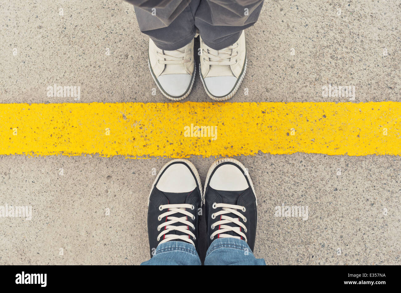 Sneakers from above. Male and female feet in sneakers from above, standing at dividing line. Stock Photo