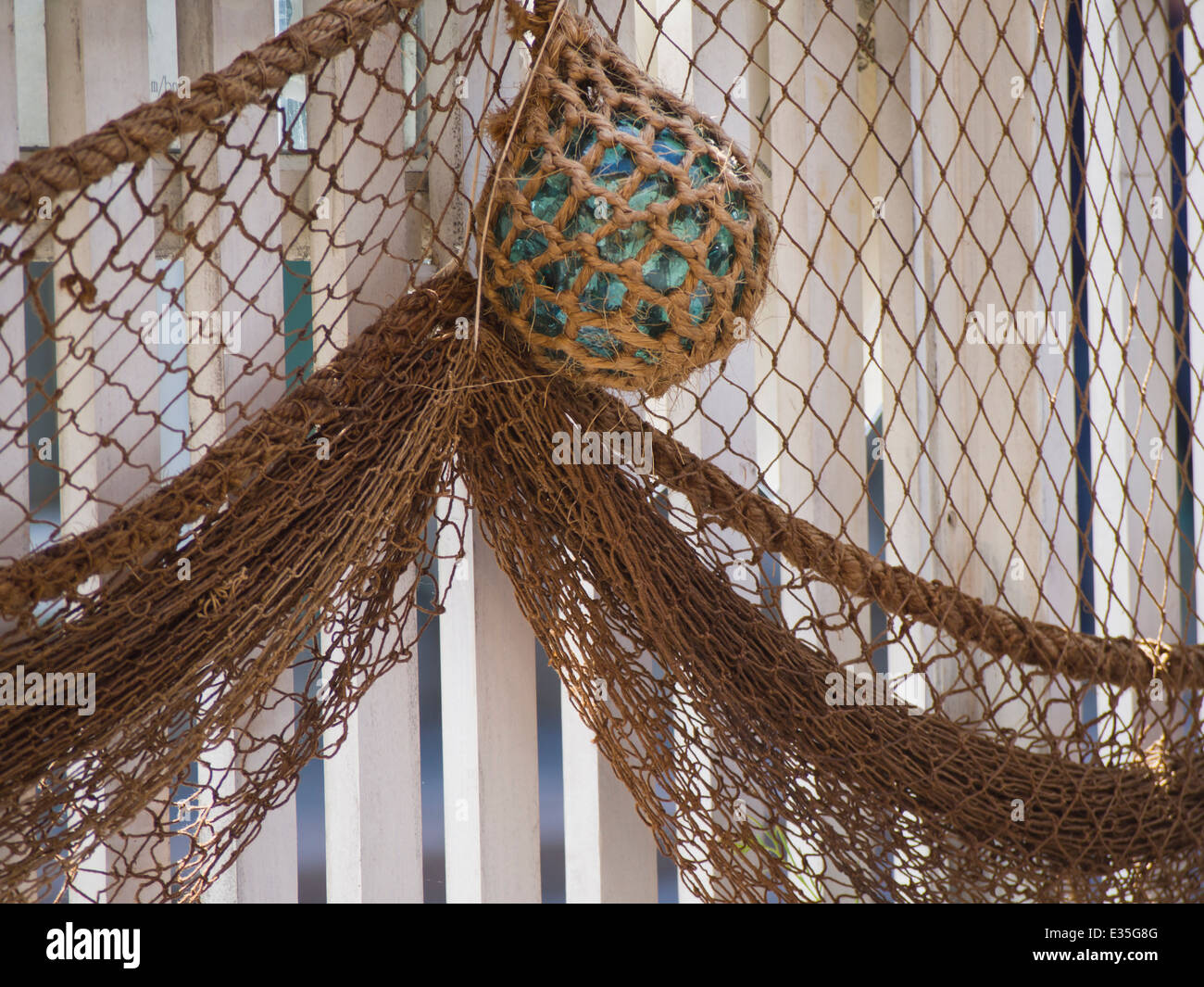 Glass float and fishing net on a picket fence, rustic decoration in an outdoors restaurant in Drobak Norway Stock Photo