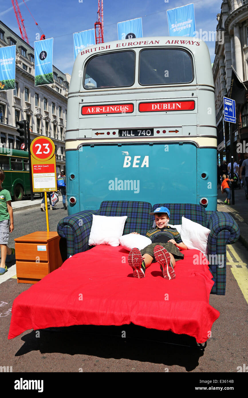 London, UK. 22nd June 2014. James from Australia relaxing on a bed beside the AEC BEA Coach MLL740 Bus in service 1953-1973 at the Year of the Bus Cavalcade in Regent Street, London celebrating the role buses have played in moving people around London. Buses were on display from 1829 to the present day. Stock Photo