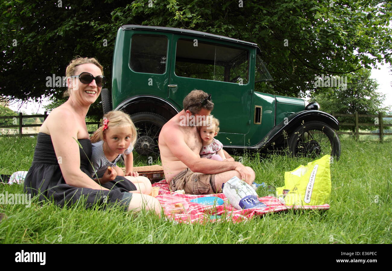 A family enjoy a picnic in the parkland surrounding Chatsworth House by their classic Austin 7 car, Peak District, Derbyshre, UK Stock Photo