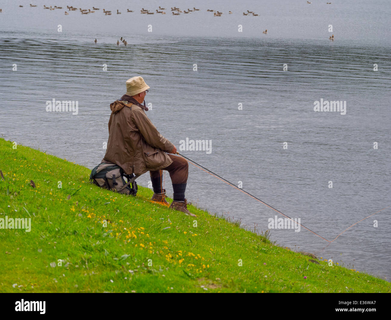 Lockwell England Man smoking a pipe fishing for trout at the Lockwood Beck reservoir ...