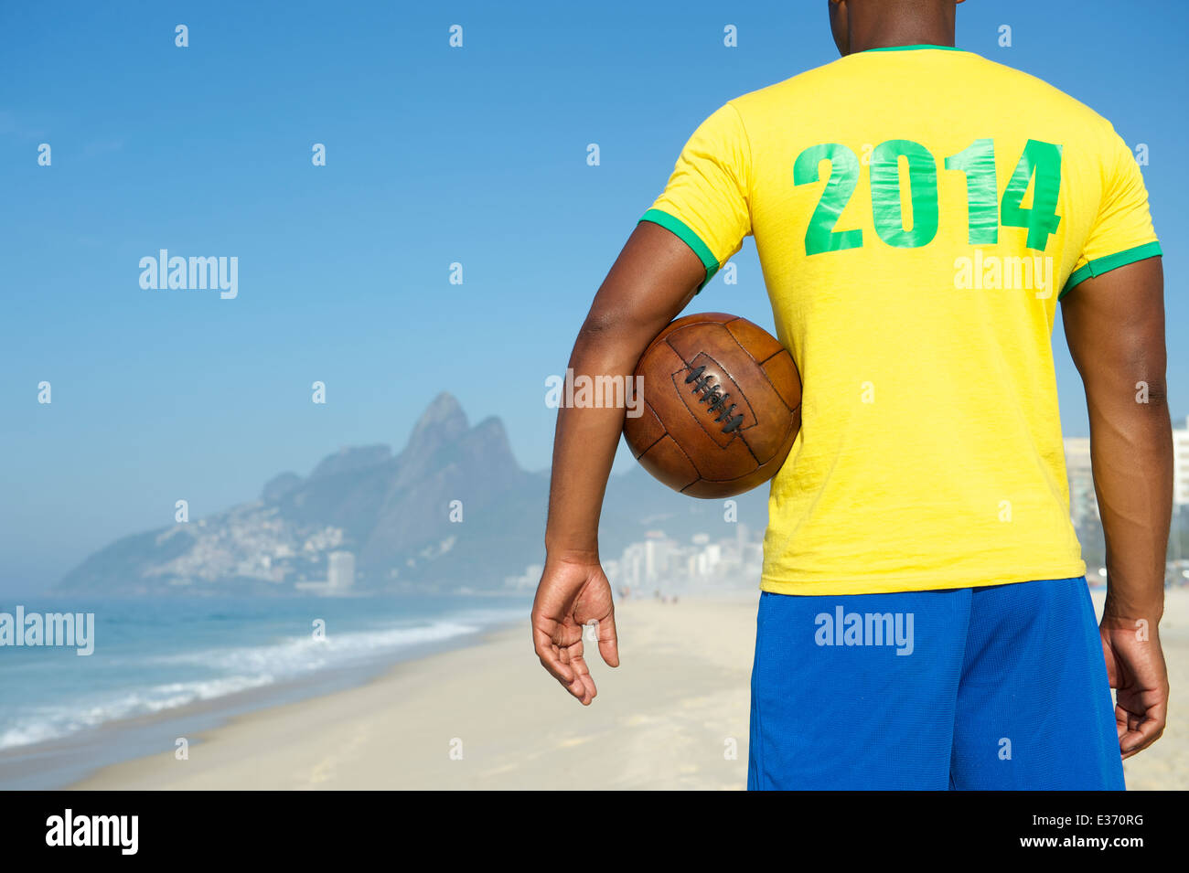 Brazil 2014 footballer in team Brazil kit holding vintage soccer ball Ipanema Beach Rio de Janeiro Stock Photo