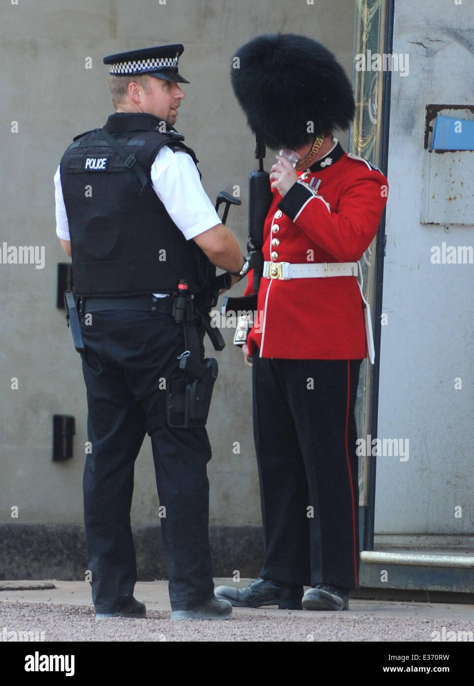 A policeman gives a Royal Guard some water as he feels the heat from