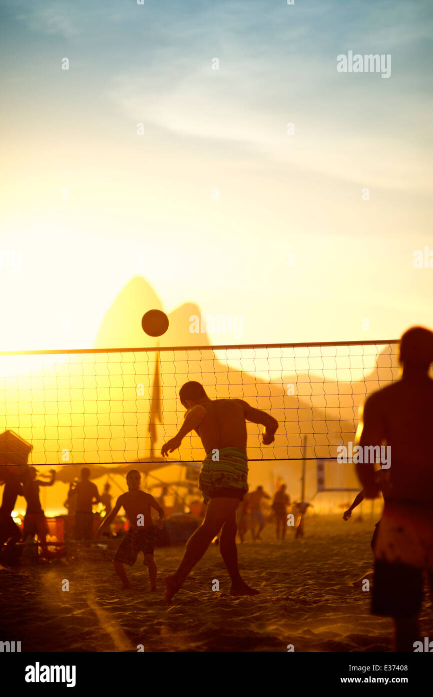 Carioca Brazilians Rio de Janeiro Brazil sunset beach volleyball game against a silhouette of Dois Irmaos Mountain on Ipanema Stock Photo