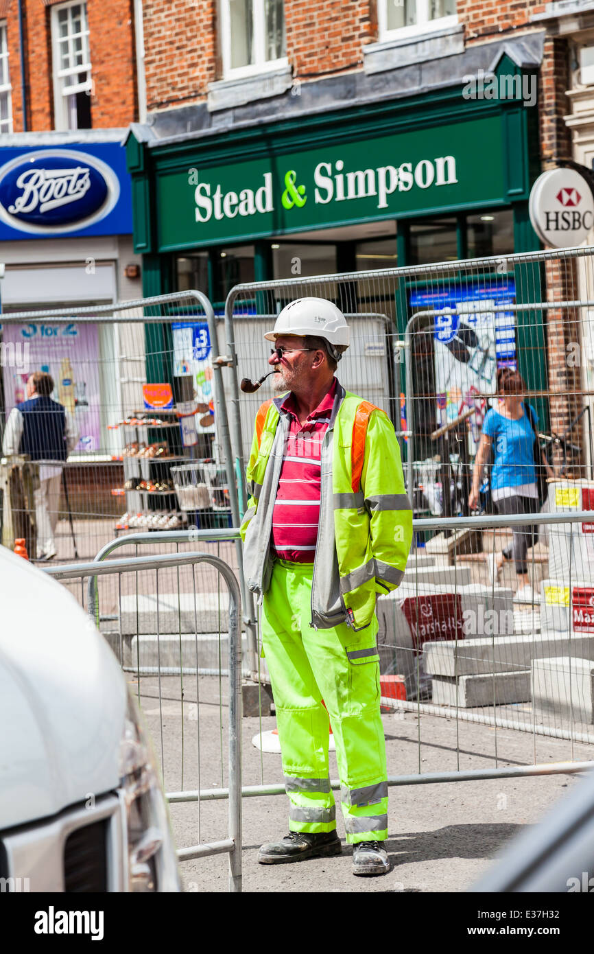 Leek, Staffordshire, England Construction worker standing with hands in pockets, a smoking pipe in his mouth Stock Photo