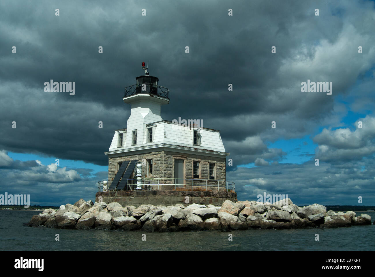 Sun breaks through clouds over Connecticut's Penfield Reef lighthouse. It is considered haunted by a keeper who drowned nearby. Stock Photo