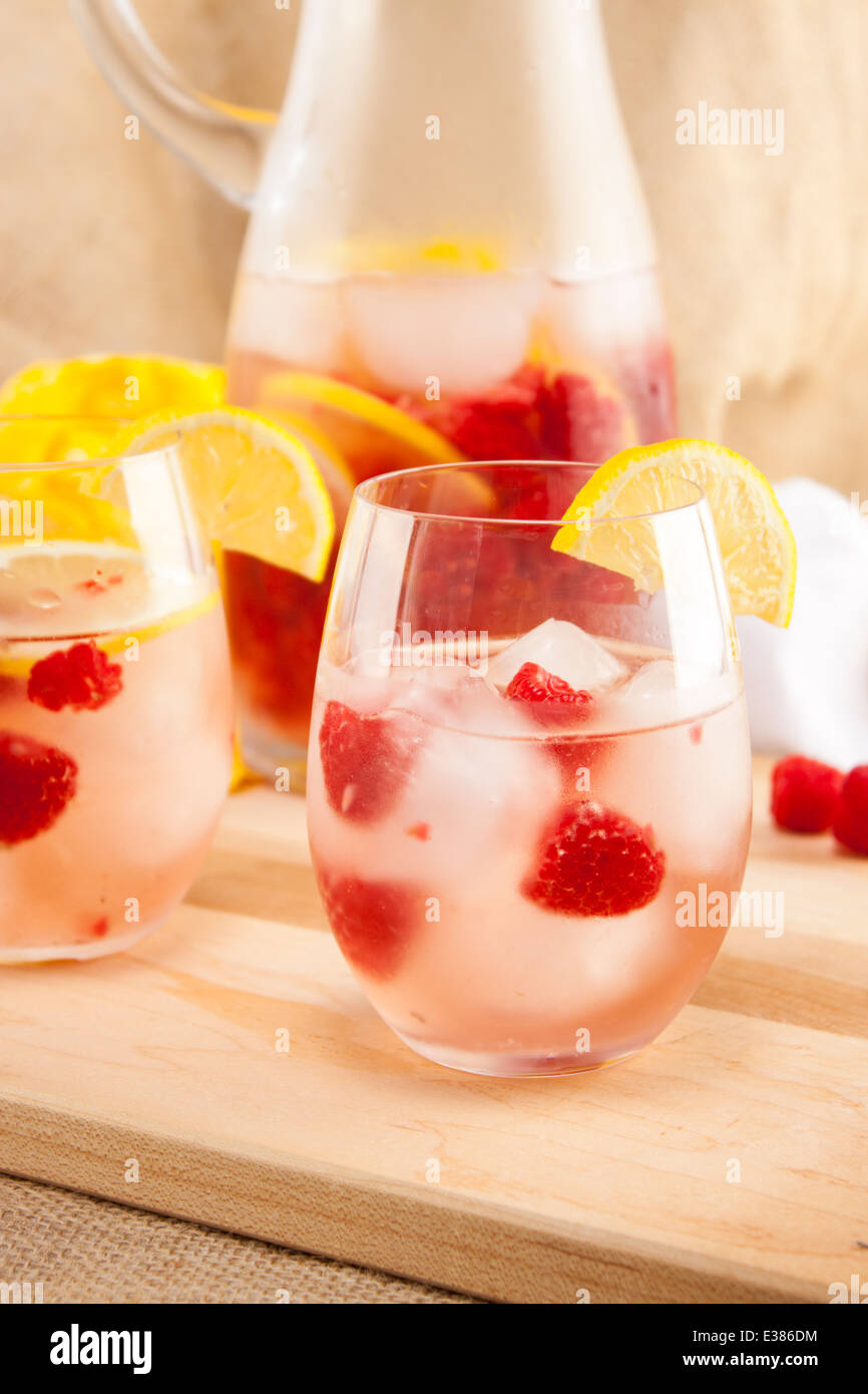 White wine sangria in glasses with raspberries and lemon wedges. Stock Photo