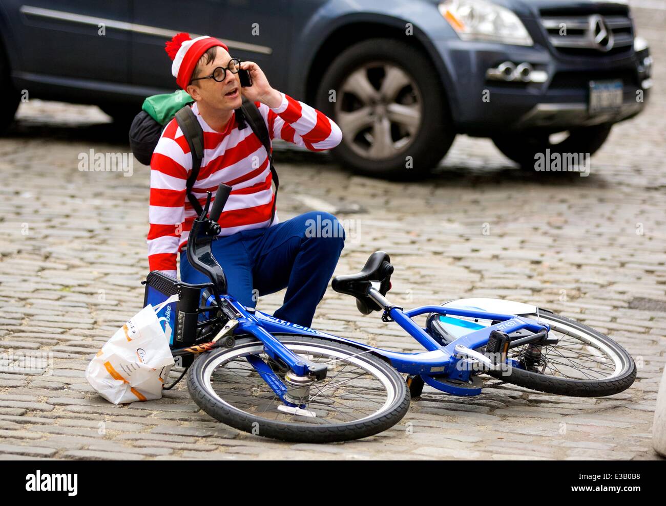A man dressed as the character Waldo from the children's book series, 'Where's Waldo?' is spotted riding a Citi Bike in the Meatpacking District. With his hands full, Waldo eventually falls off his bicycle to the ground  Featuring: Waldo,Wally Where: New Stock Photo