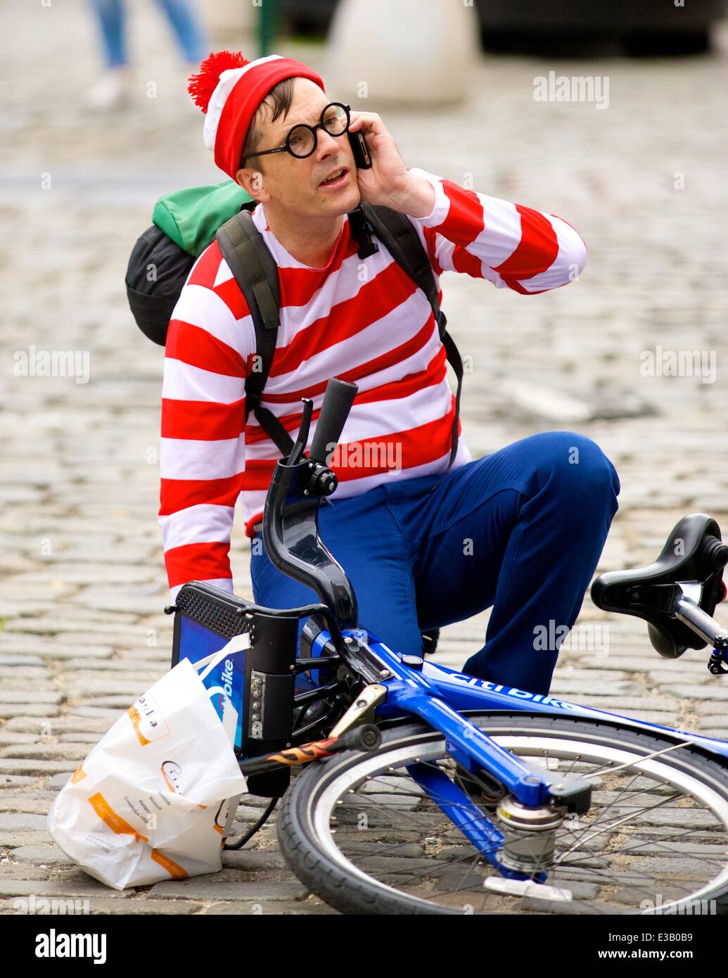 A man dressed as the character Waldo from the children's book series, 'Where's Waldo?' is spotted riding a Citi Bike in the Meatpacking District. With his hands full, Waldo eventually falls off his bicycle to the ground  Featuring: Waldo,Wally Where: New York City, NY, United States When: 14 Sep 2013 Stock Photo