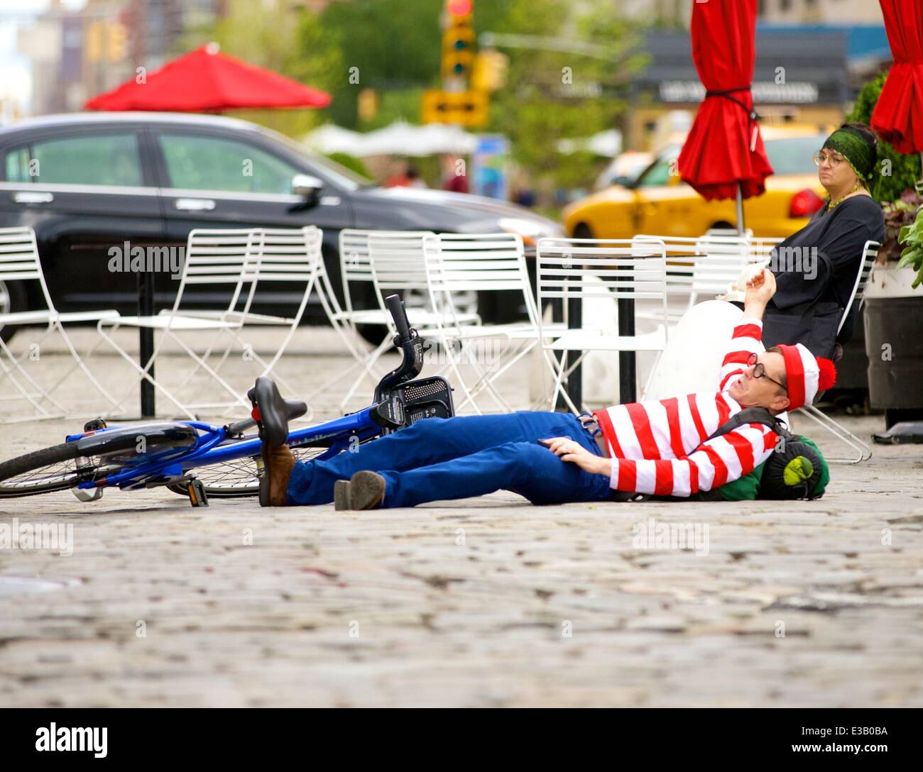 A man dressed as the character Waldo from the children's book series, 'Where's Waldo?' is spotted riding a Citi Bike in the Meatpacking District. With his hands full, Waldo eventually falls off his bicycle to the ground  Featuring: Waldo,Wally Where: New York City, NY, United States When: 14 Sep 2013.com Stock Photo