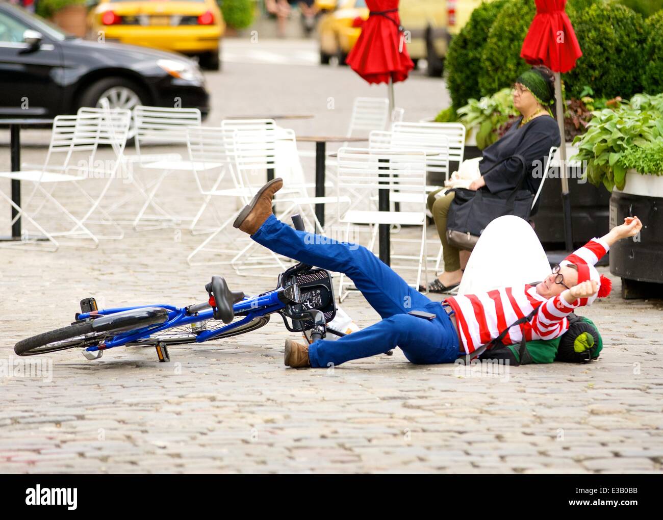 A man dressed as the character Waldo from the children's book series, 'Where's Waldo?' is spotted riding a Citi Bike in the Meatpacking District. With his hands full, Waldo eventually falls off his bicycle to the ground  Featuring: Waldo,Wally Where: New York City, NY, United States When: 14 Sep 2013 Stock Photo