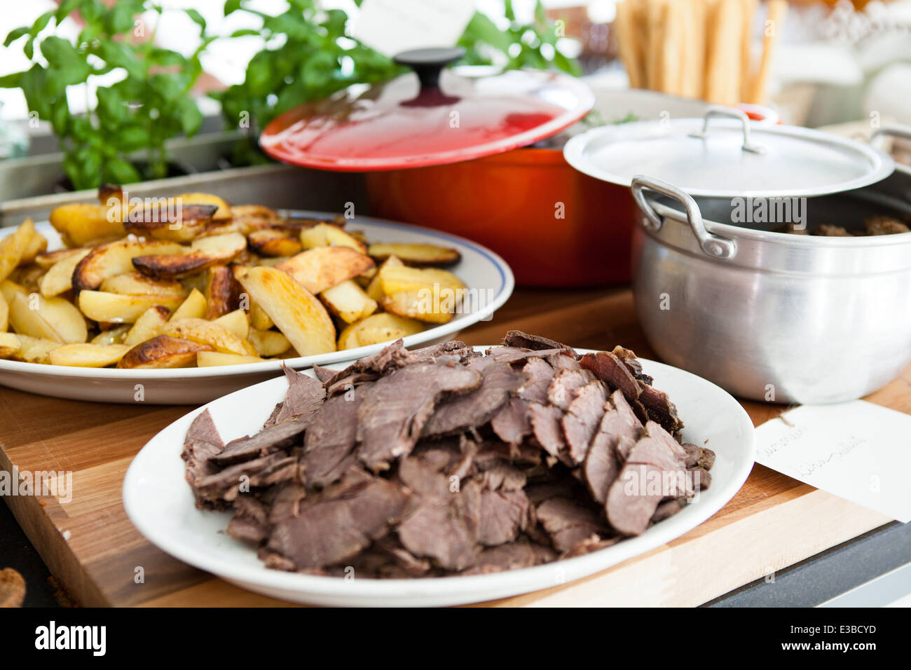 Closeup of plates of cooked meat and thick style french fries on table ready for serving at dinner party Stock Photo