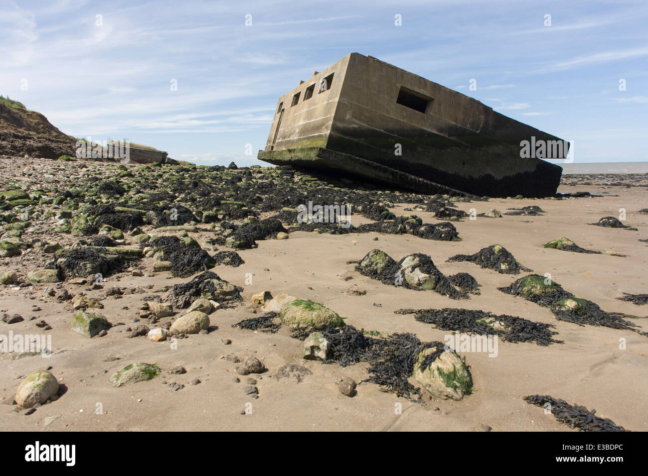 WW2-era concrete pillbox defence structure lies on the beach after coastal erosion at Warden Point, Isle of Sheppey, Kent. Stock Photo