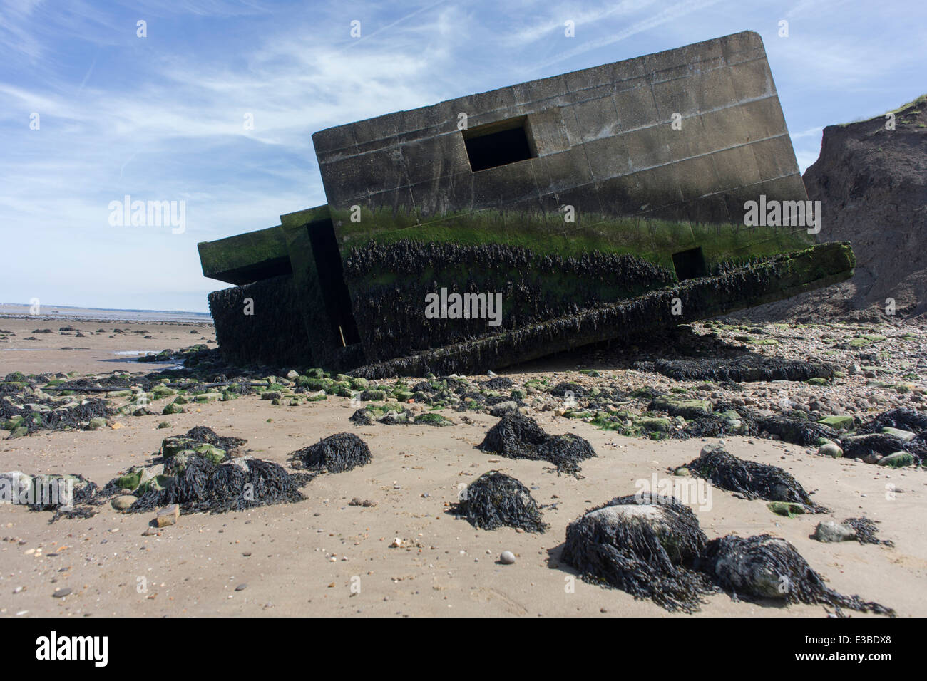 WW2era concrete pillbox defence structure lies on the beach after