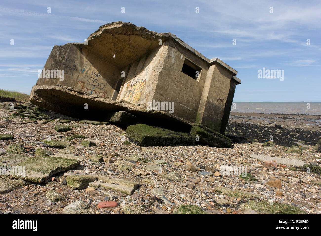 WW2era concrete pillbox defence structure lies on the beach after