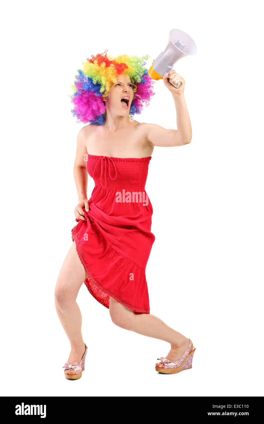 Full length portrait of a woman with wig shouting on a megaphone Stock Photo