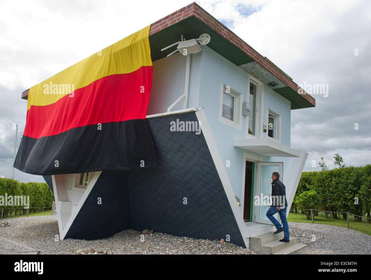 Usedom, Germany. 23rd June, 2014. Employees of the tourist attraction 'The World stands on its Head' have hoisted a German flag above the upside down house in Trassenheide on Usedom, Germany, 23 June 2014. The flag measures about four times nine metres and, in accordance with the upside down position of the house, has been attached the wrong way round. Photo: STEFAN SAUER/DPA/Alamy Live News Stock Photo