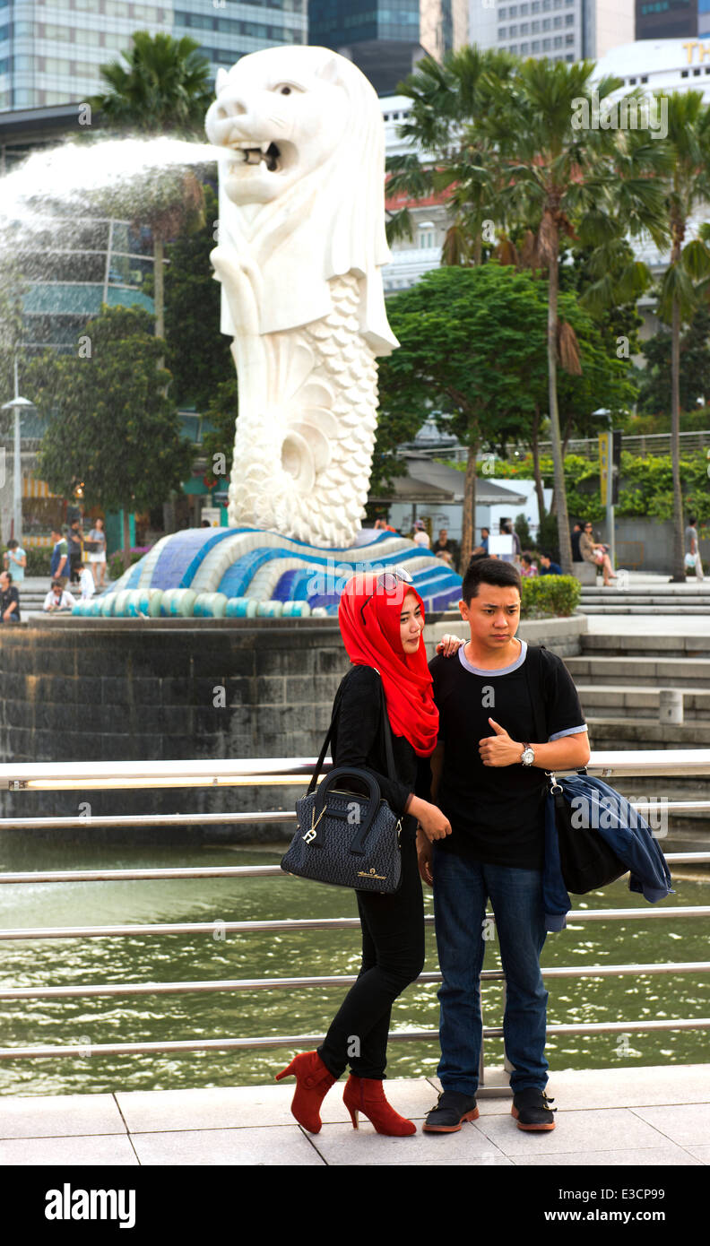Muslim couple stand in front of Singapore's Merlion. Stock Photo