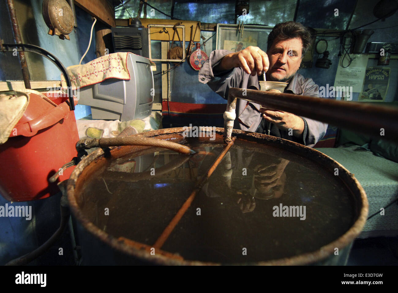 A Bulgarian man checks the alcoholic quality at a small home raki ...